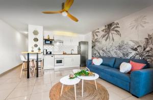 La Créola New! Grand Case - vue mer - appart 4p - King size في غراند كيس: غرفة معيشة مع أريكة زرقاء ومطبخ