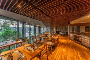 un restaurante con mesas y sillas de madera y ventanas en The Trees, Kandy en Kandy