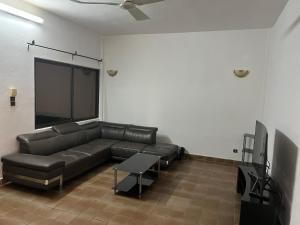 a living room with a leather couch and a flat screen tv at Luxious Cosy Apart 2 Bedroom Cotonou Centre in Cotonou
