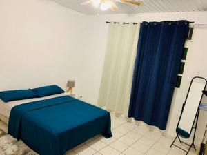 1 dormitorio con cama azul y cortina azul en Sublime T4 à kourou avec piscine en Kourou