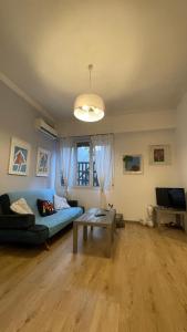 uma sala de estar com um sofá azul e uma mesa em Cozy apartment ideally located city center and Megaron Moussikis metro station em Atenas