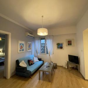 sala de estar con sofá azul y mesa en Cozy apartment ideally located city center and Megaron Moussikis metro station, en Atenas