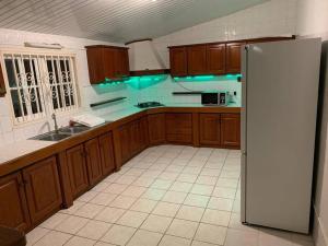 a kitchen with wooden cabinets and a refrigerator at Sublime T4 à kourou avec piscine in Kourou