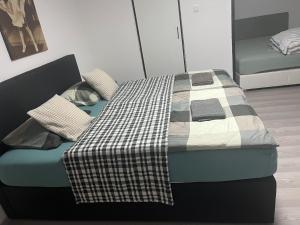 a bed with a checkered blanket and pillows on it at Apartmánek Patricie room with kitchenette suitable for 2 adults and 2 children in Mikulov