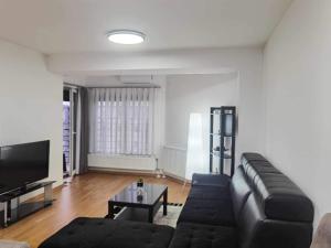 ein Wohnzimmer mit einem schwarzen Sofa und einem TV in der Unterkunft Fantasy - Strumica in Strumica
