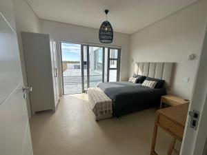 a bedroom with a bed and a view of a balcony at Atlantic Corner in Yzerfontein