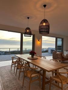 a dining room with a table and chairs and windows at Atlantic Corner in Yzerfontein