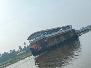 a boat with a building on the side of a river at SR Houseboats Kumarakom in Kumarakom