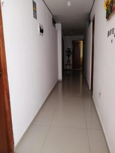 un couloir vide avec des murs blancs et du carrelage blanc au sol. dans l'établissement Hotel Huanchaco, à Trujillo