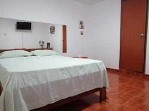 1 dormitorio con 1 cama con edredón blanco en Hotel Huanchaco, en Trujillo