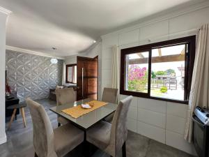 uma sala de jantar com uma mesa e cadeiras e uma janela em Casa no centro de Xangrilá em Xangri-lá