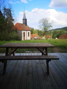 a wooden picnic table on a wooden deck with a church at Gîte La Lisière in Sparsbach