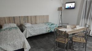 Un dormitorio con dos camas y un televisor en la pared. en Cabañas Olluhuasi, en Valle Hermoso