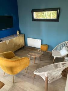 a living room with chairs and tables and a tv at Woody Lodge in Salbris