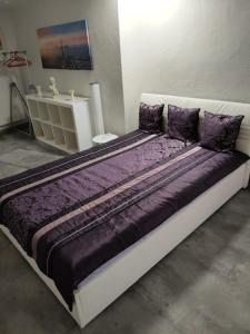 uma cama grande com almofadas roxas num quarto em Gemütliche Einliegerwohnung im Fachwerkhaus em Bröckel