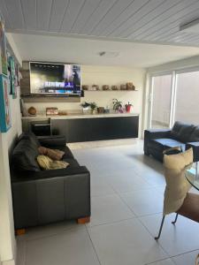 a living room with a black couch and a kitchen at Linda Casa com amplo jardim! in Curitiba