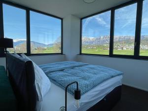 a bedroom with a bed and three windows with mountains at Laurin‘s in Schaanwald