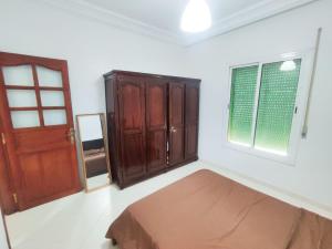 a bedroom with a bed and a wooden door at SkyRise 1 Khemisset 2 bedrooms in Khemisset