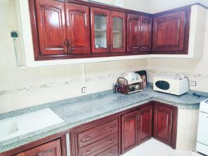 a kitchen with wooden cabinets and a microwave at SkyRise 1 Khemisset 2 bedrooms in Khemisset