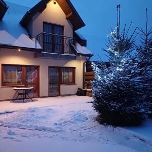 uma árvore de Natal em frente a uma casa na neve em Willa Trzy Podkowy em Krościenko