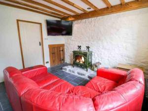 un sofá rojo en la sala de estar con chimenea en Pandy Farmhouse - Panoramic mountain views within Snowdonia's National Park - 4x4 recommended en Dolgellau