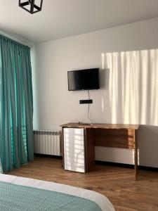 a bedroom with a television on a dresser with a bed at Hotel Grand View in Stepantsminda