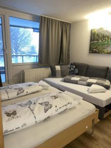 a room with three beds and a couch at FeWo Waldsee mit Pool und Sauna inklusive in Sankt Englmar