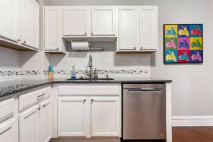 a kitchen with white cabinets and a stainless steel dishwasher at Historic Family Getaway, 5 Star Location, Royal Beds in Kansas City