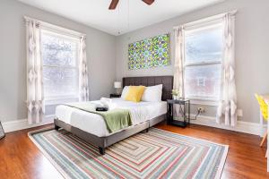 1 Schlafzimmer mit einem Bett, 2 Fenstern und einem Teppich in der Unterkunft Historic Family Getaway, 5 Star Location, Royal Beds in Kansas City