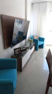 un soggiorno con 2 sedie blu e una TV a schermo piatto di Apartamento vista Mar a Salvador