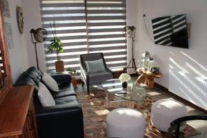 a living room with a leather couch and a glass table at TuarriendoCL-MPHC304 Cómodo Departamento Puerto Varas in Puerto Varas