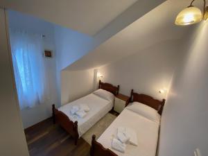 zwei Betten in einem kleinen Zimmer mit Fenster in der Unterkunft Villa Ana in Sevid