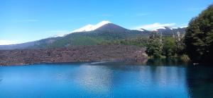a large blue lake with a mountain in the background at Refugio Kiñeco in Conguillio