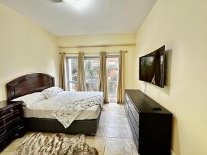 a bedroom with a bed and a television and a window at Luxurious Retreat in Port-of-Spain