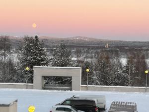 une voiture garée sur un parking avec la lune dans le ciel dans l'établissement Keskustan kaksio, à Rovaniemi