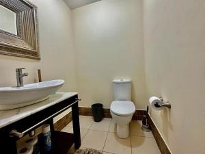 a bathroom with a white toilet and a sink at Luxurious Retreat in Port-of-Spain