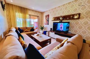 a living room with a couch and a tv at Luxurious Stay at Prestigia Golf Marrakech with Golf Course, Pool, and Breathtaking Atlas Mountains View in Marrakesh