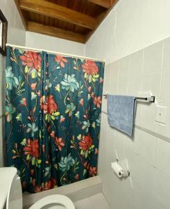 a bathroom with a shower curtain with a flower pattern at Inti Wasi in San Carlos