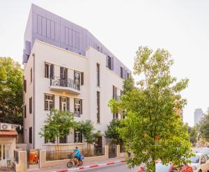 a man riding a bike in front of a white building at Boutique Patio appalments next to Rothschild blvd in Tel Aviv
