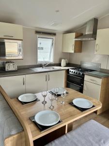 a kitchen with a table with plates and wine glasses at On the Lake Weeley in Weeley