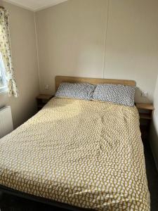 a bed in a bedroom with a bedspread on it at On the Lake Weeley in Weeley