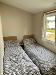 two beds in a small room with a window at On the Lake Weeley in Weeley