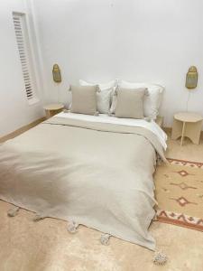 een slaapkamer met een groot bed met witte lakens en kussens bij Dar Yasmina in Sidi Ifni