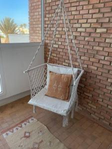 a white swing with a pillow on a brick wall at Dar Yasmina in Sidi Ifni
