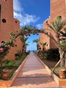 a walkway between two brick buildings with palm trees at Dar Yasmina in Sidi Ifni