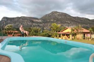 a man sitting on a chair next to a swimming pool at Pousada Bela Vista do Ismail - Lapinha da Serra in Santana do Riacho