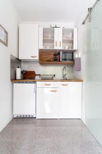 una cocina con armarios blancos y fregadero en Moderne 2-Zimmer Wohnung, en Gratwein