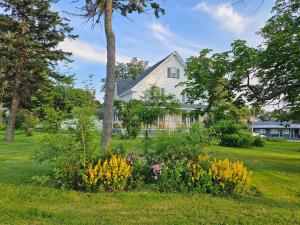 une maison blanche avec des fleurs dans la cour dans l'établissement Sunflower Guest Suites, à Summerside