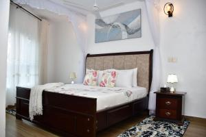 Zuri Luxe 2BR Beach apt.-Malindi في ماليندي: غرفة نوم بسرير كبير وبجدران بيضاء