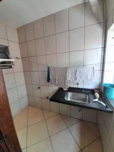 uma casa de banho com um lavatório e uma parede em azulejo em Excelente Localização em Jacaraípe em Serra